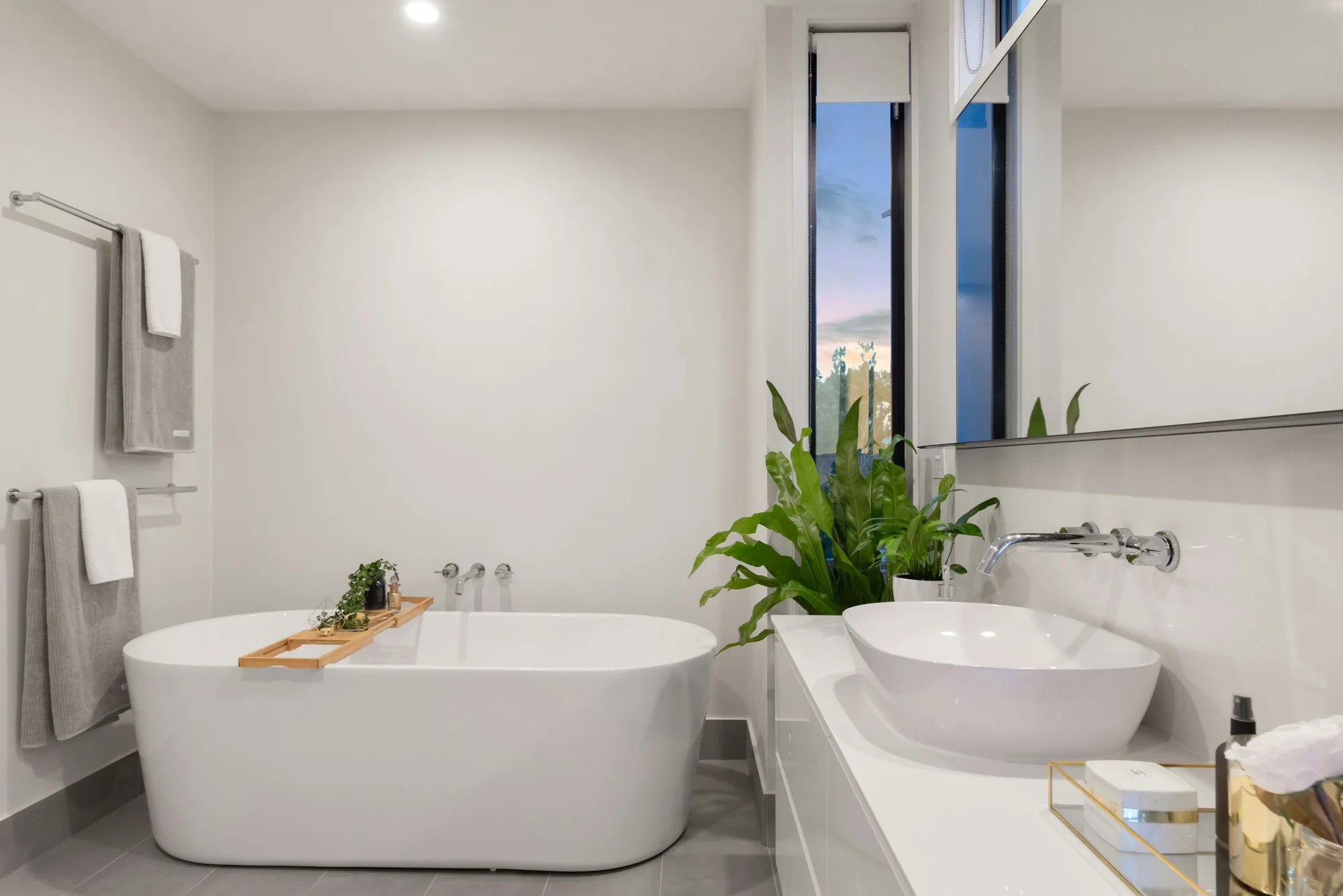 Fresh bathroom with a white bath, basin and leafy plants