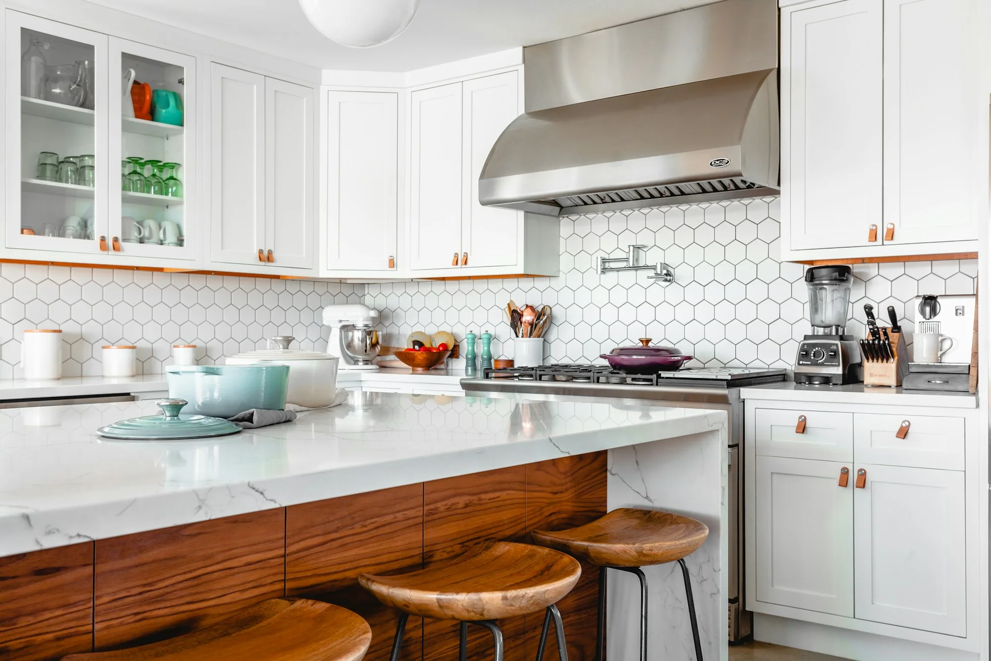 Bright kitchen with clean stone benchtops, white cabinets and timber stools
